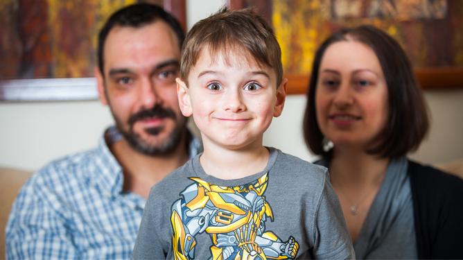 Young boy who has Duchenne muscular dystrophy smiles with his parents
