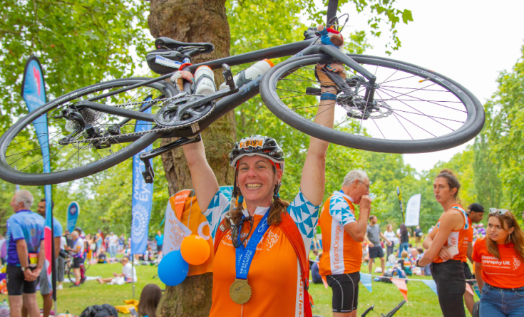 Woman holding bike in air in celebration after completing RideLondon